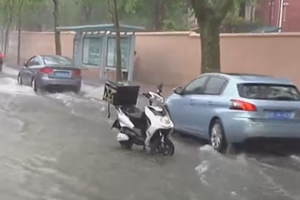 温暖！古力井盖被大雨冲错位 外卖小哥雨中警示过往车辆